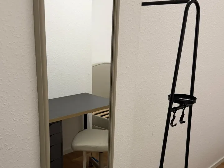 Wandspiegel und schwarzer Garderobenständer gerade an der Wand befestigt