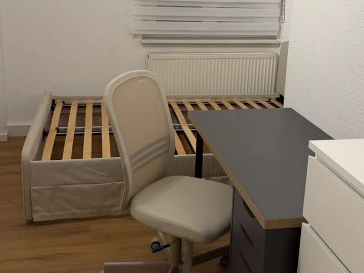 Fertig eingerichtetes Zimmer mit Bett, Lattenrost, Schreibtisch, Bürostuhl und Kommode
